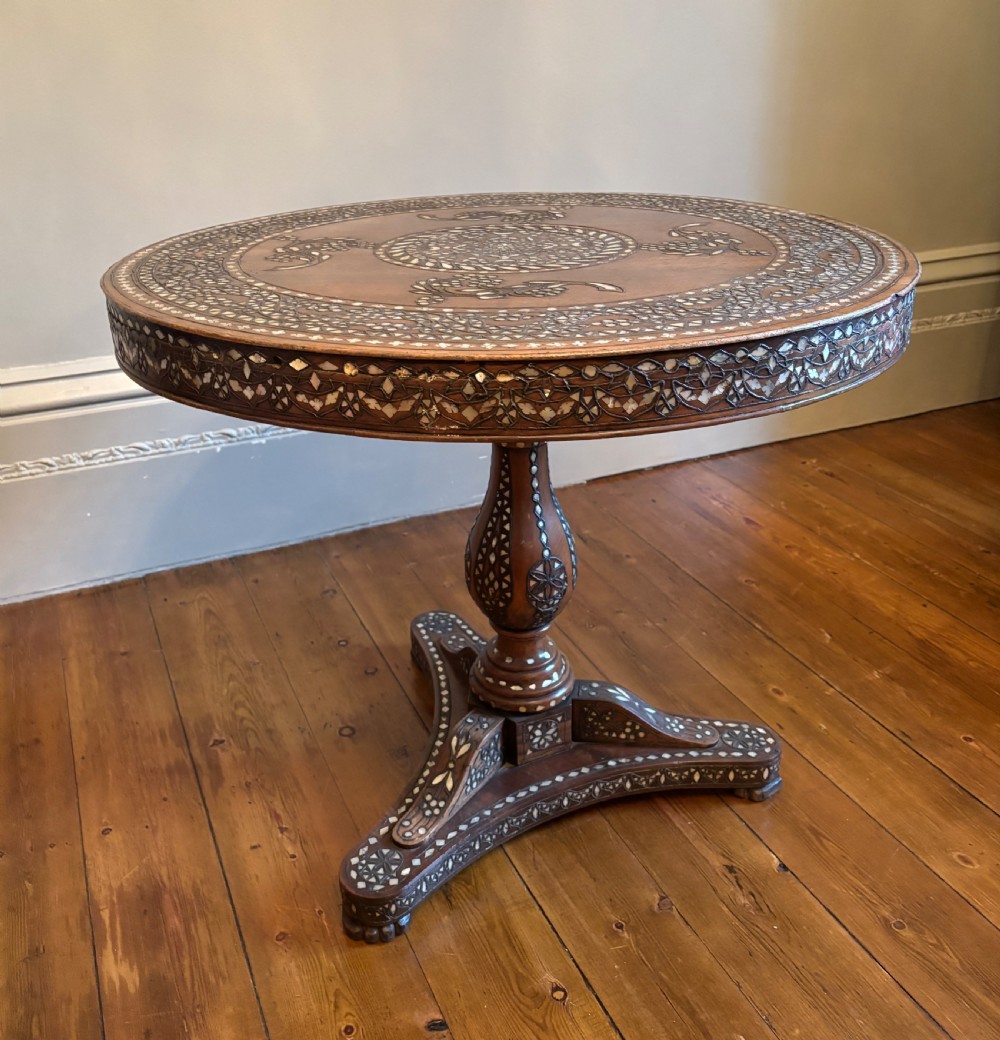 A 19th-century round Anglo-Indian pedestal table featuring mother-of-pearl inlay across the circular top, apron, turned column, and tripod base. View XVI