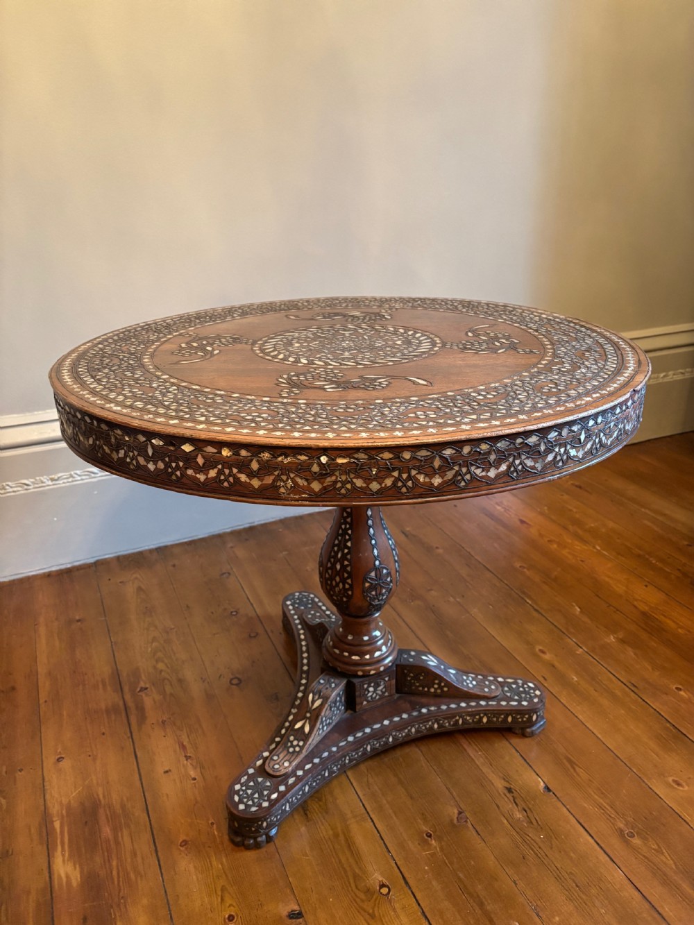 A 19th-century round Anglo-Indian pedestal table featuring mother-of-pearl inlay across the circular top, apron, turned column, and tripod base. View XVII