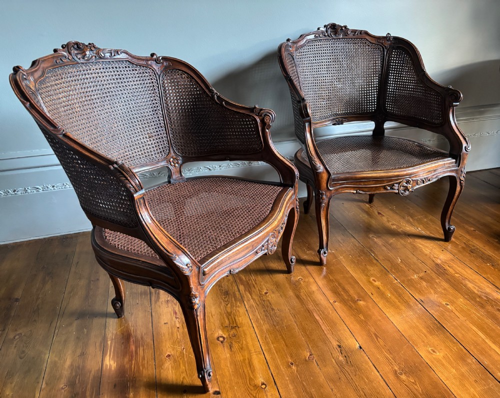 A pair of Louis XV style carved wooden bergere armchairs featuring woven cane backs and purple velvet seat cushions. View V