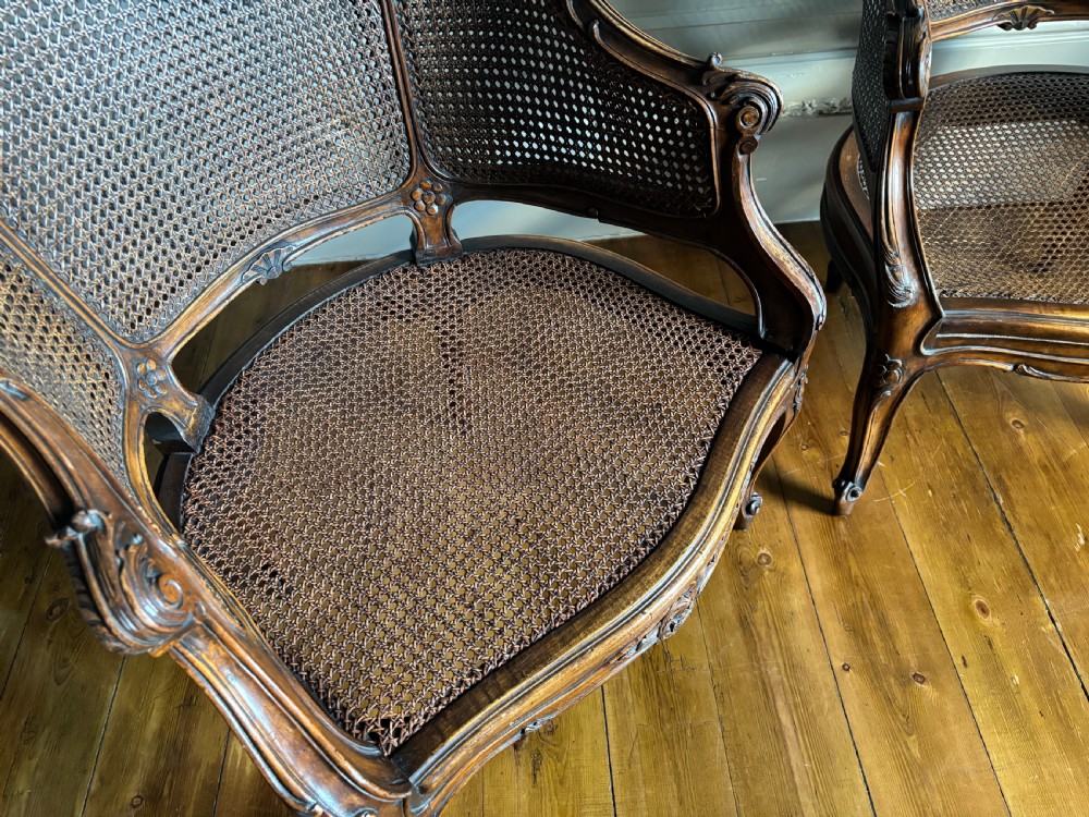 A pair of Louis XV style carved wooden bergere armchairs featuring woven cane backs and purple velvet seat cushions. View VI