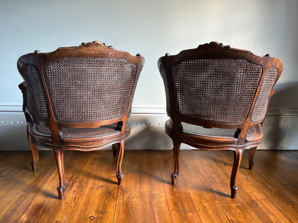 A pair of Louis XV style carved wooden bergere armchairs featuring woven cane backs and purple velvet seat cushions. View VIII