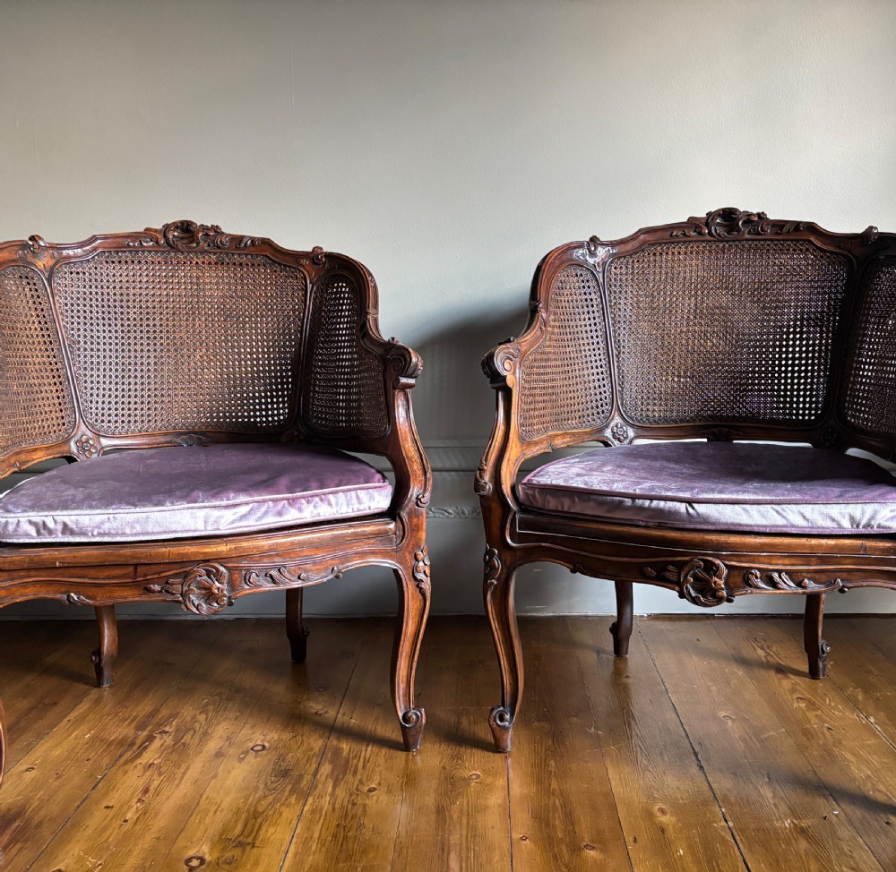 A pair of Louis XV style carved wooden bergere armchairs featuring woven cane backs and purple velvet seat cushions. View IX