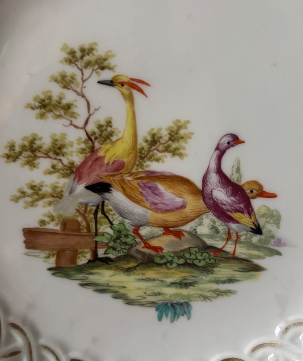 A circular Meissen porcelain cabinet plate featuring a reticulated openwork lattice rim accented with gilded cartouches and hand-painted exotic birds in the centre. View II