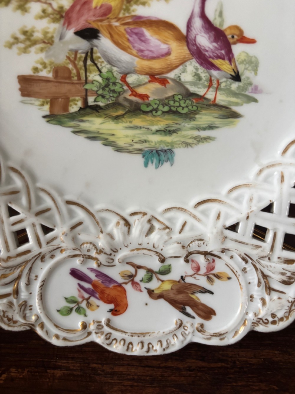 A circular Meissen porcelain cabinet plate featuring a reticulated openwork lattice rim accented with gilded cartouches and hand-painted exotic birds in the centre. View III