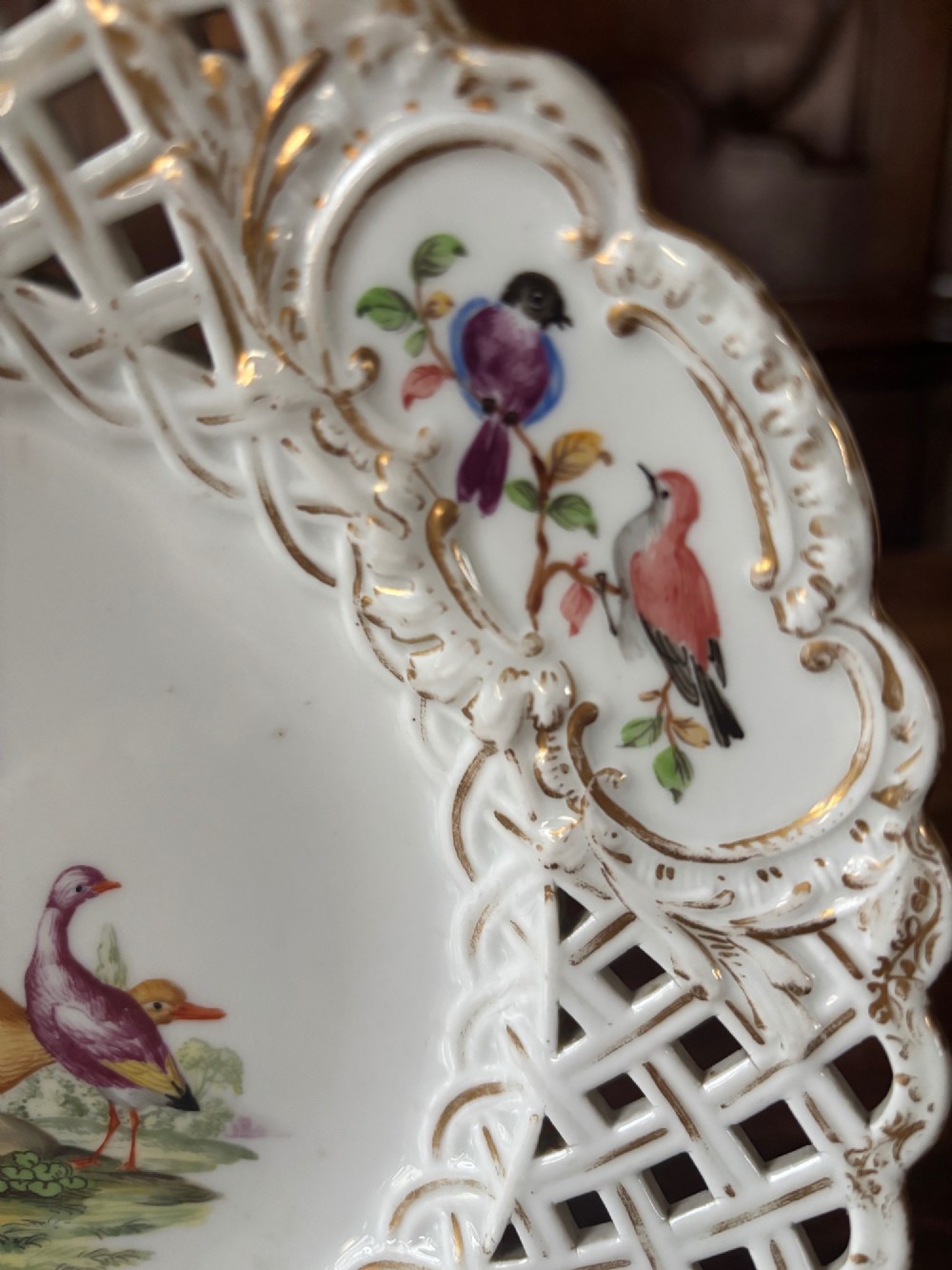 A circular Meissen porcelain cabinet plate featuring a reticulated openwork lattice rim accented with gilded cartouches and hand-painted exotic birds in the centre. View V