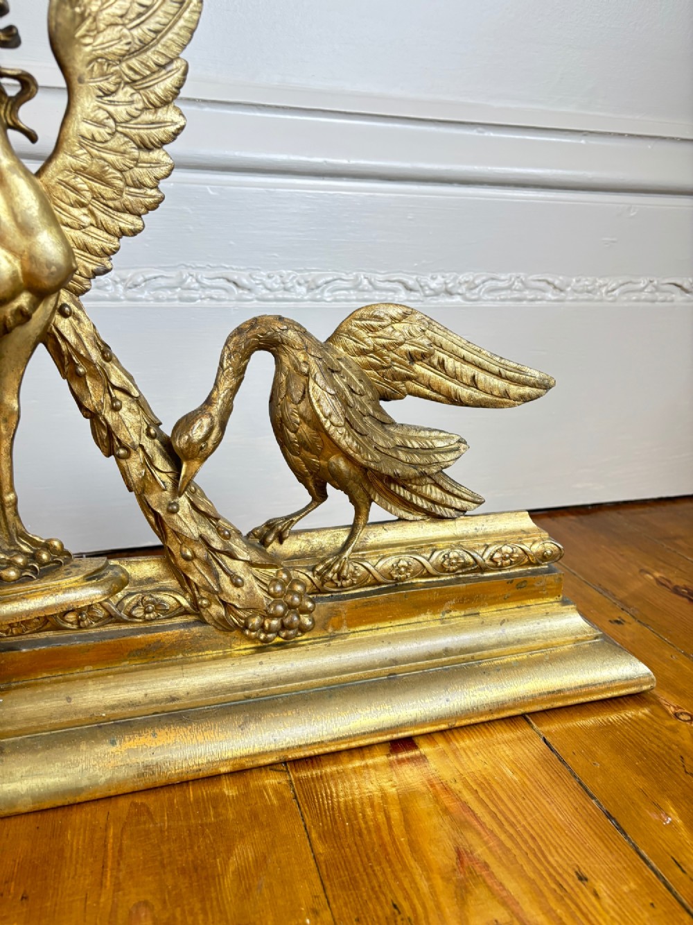 A long gilt bronze fireplace fender featuring winged sphinxes on either side, foliate scrollwork, and a central classical urn on a stepped base. View V