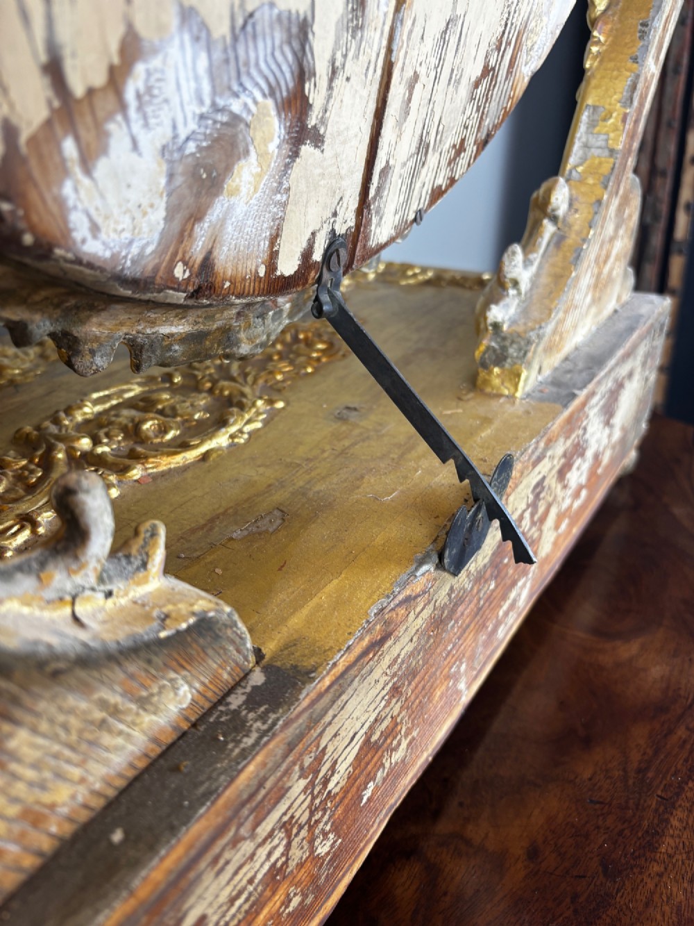 An 18th-century Italian giltwood table mirror featuring an oval glass frame supported by ornate scroll carved arms atop a single-drawer plinth base. View VII