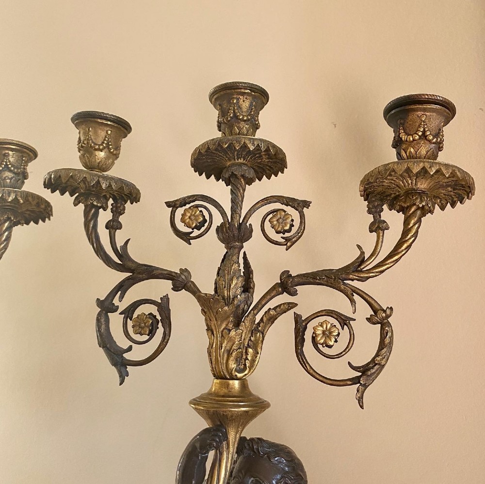A pair of late Louis XVI style candelabra featuring dark patinated bronze putti holding multi-arm gilt bronze candle holders, mounted on circular fluorspar pedestals with ormolu floral swags. View IV