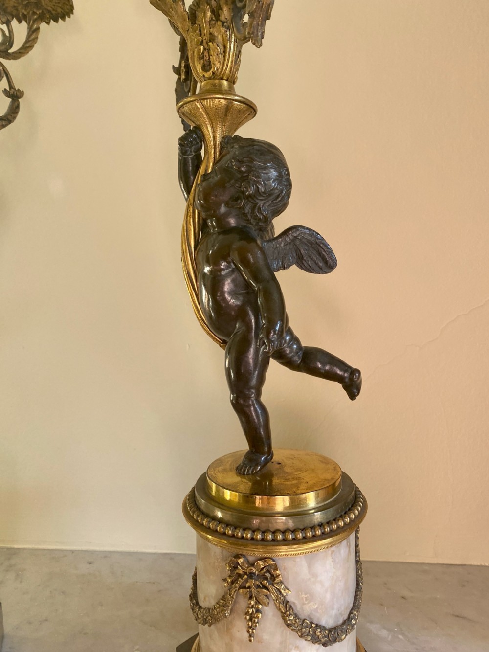 A pair of late Louis XVI style candelabra featuring dark patinated bronze putti holding multi-arm gilt bronze candle holders, mounted on circular fluorspar pedestals with ormolu floral swags. View V