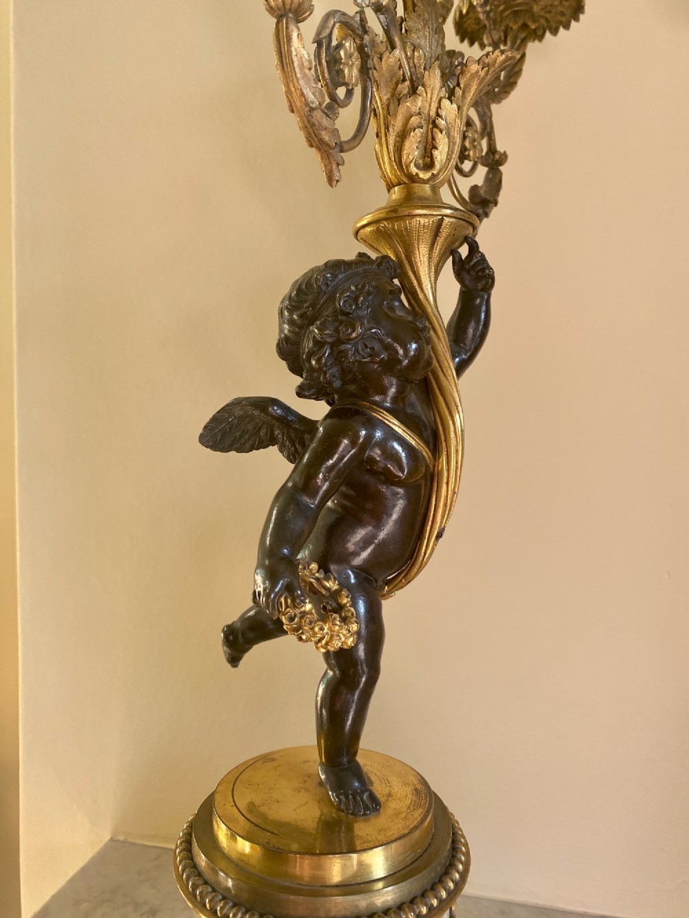 A pair of late Louis XVI style candelabra featuring dark patinated bronze putti holding multi-arm gilt bronze candle holders, mounted on circular fluorspar pedestals with ormolu floral swags. View VI