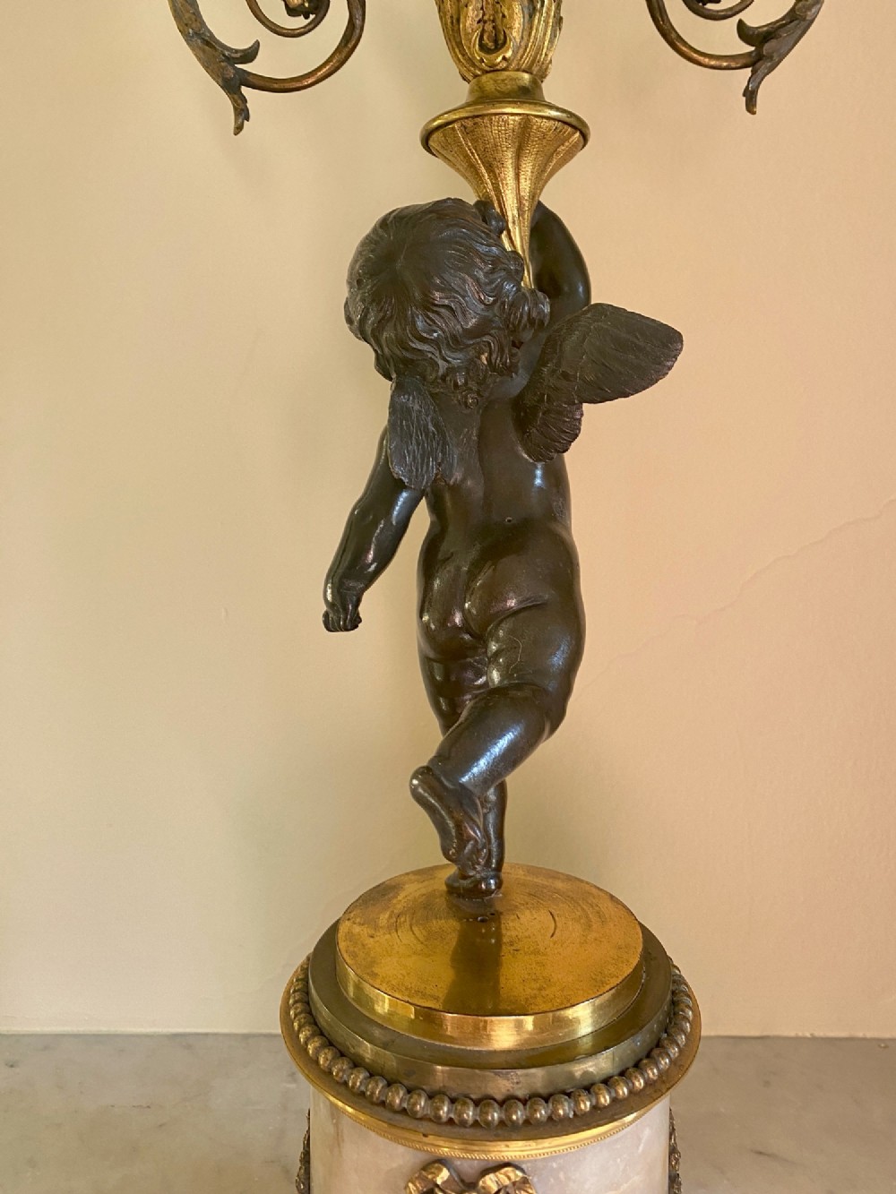 A pair of late Louis XVI style candelabra featuring dark patinated bronze putti holding multi-arm gilt bronze candle holders, mounted on circular fluorspar pedestals with ormolu floral swags. View VII
