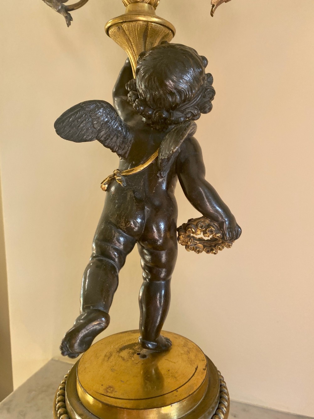 A pair of late Louis XVI style candelabra featuring dark patinated bronze putti holding multi-arm gilt bronze candle holders, mounted on circular fluorspar pedestals with ormolu floral swags. View VIII