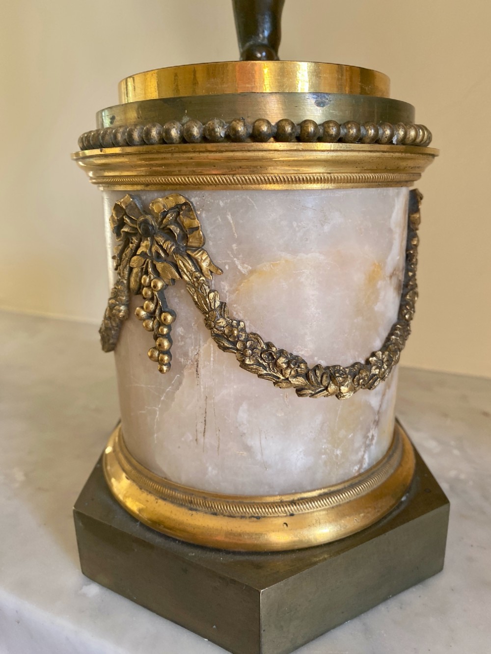 A pair of late Louis XVI style candelabra featuring dark patinated bronze putti holding multi-arm gilt bronze candle holders, mounted on circular fluorspar pedestals with ormolu floral swags. View IX