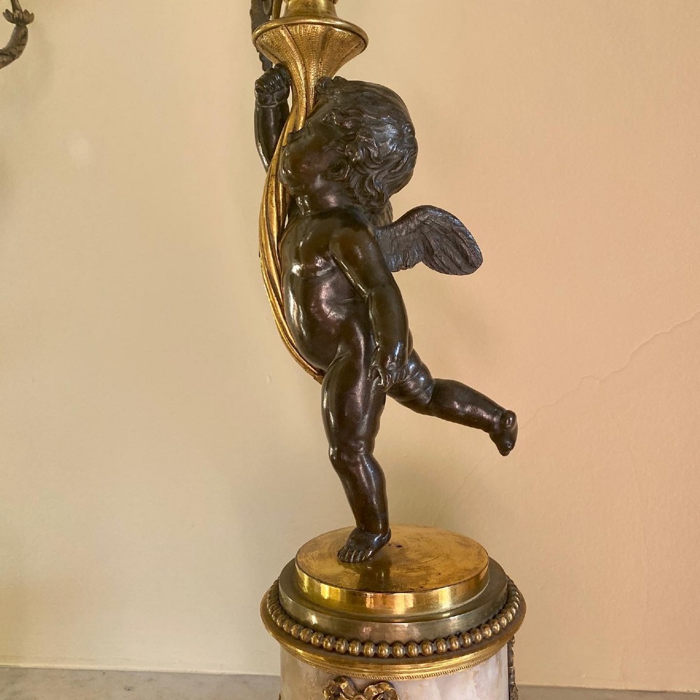 A pair of late Louis XVI style candelabra featuring dark patinated bronze putti holding multi-arm gilt bronze candle holders, mounted on circular fluorspar pedestals with ormolu floral swags. View XIV
