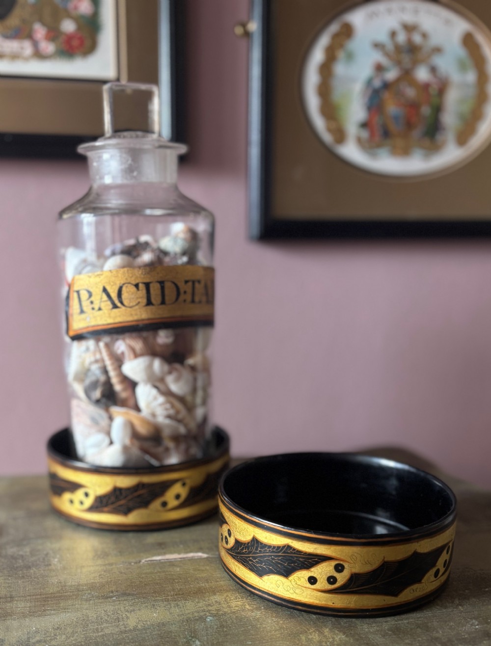 A pair of circular Regency black lacquered papier-mache wine coasters decorated with hand-painted gilded foliage motifs around the outer rim.