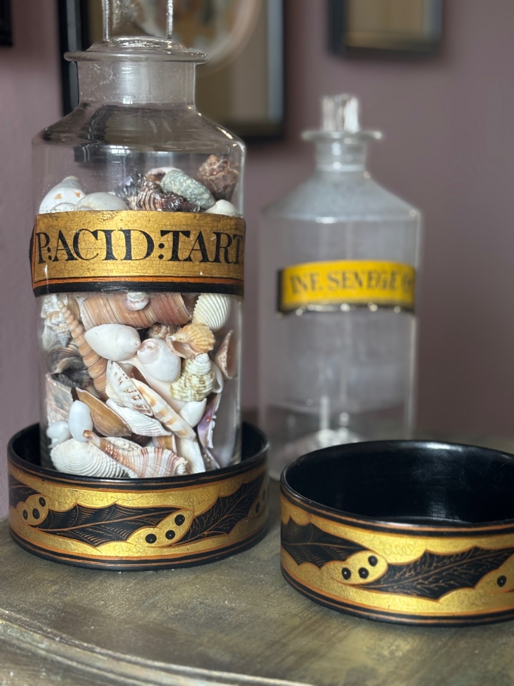 A pair of circular Regency black lacquered papier-mache wine coasters decorated with hand-painted gilded foliage motifs around the outer rim. View V