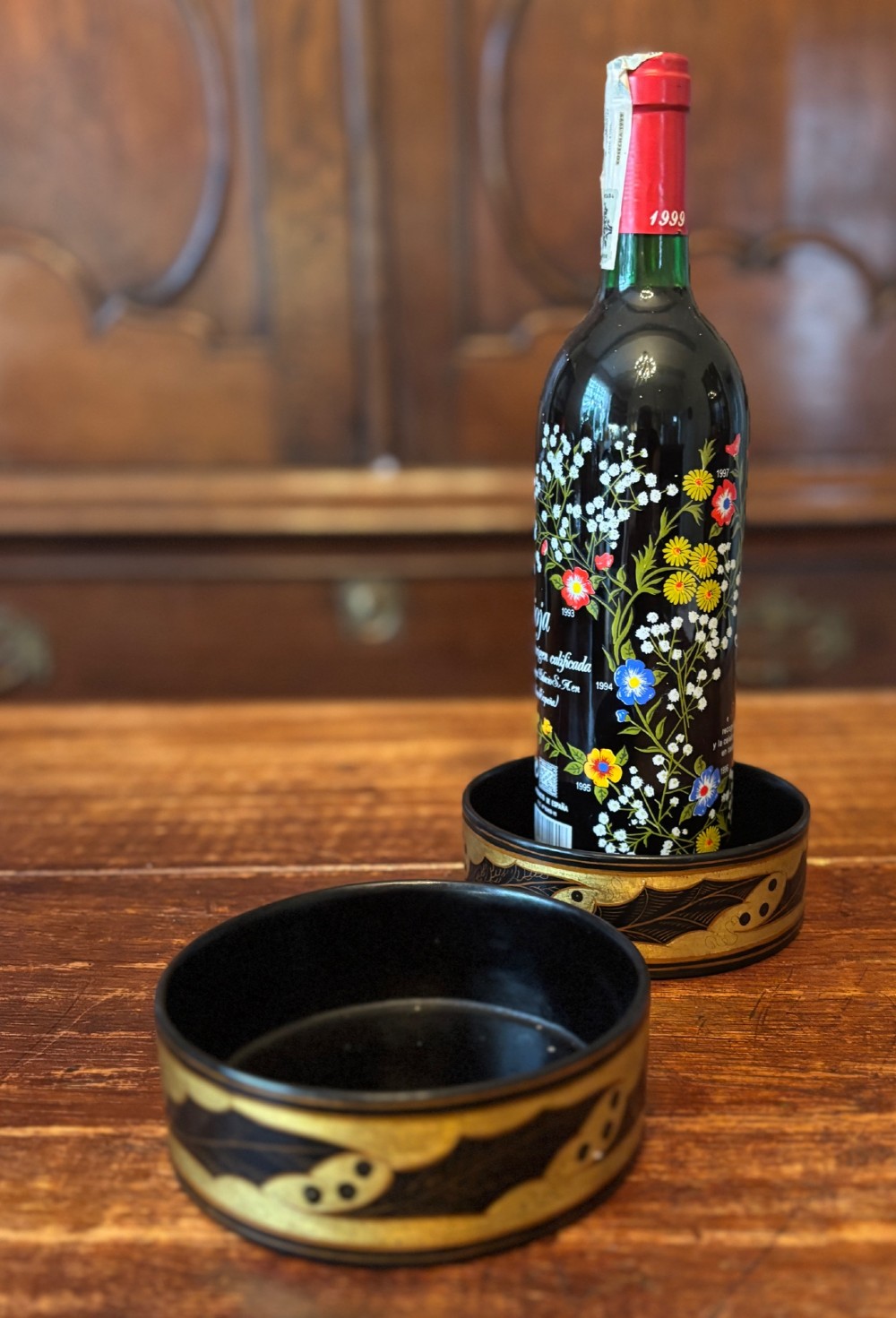 A pair of circular Regency black lacquered papier-mache wine coasters decorated with hand-painted gilded foliage motifs around the outer rim. View IX