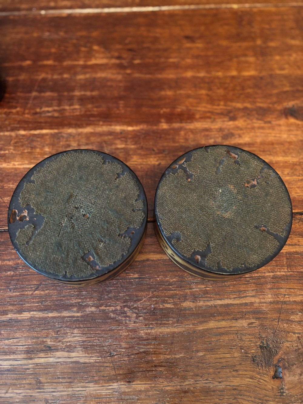 A pair of circular Regency black lacquered papier-mache wine coasters decorated with hand-painted gilded foliage motifs around the outer rim. View X