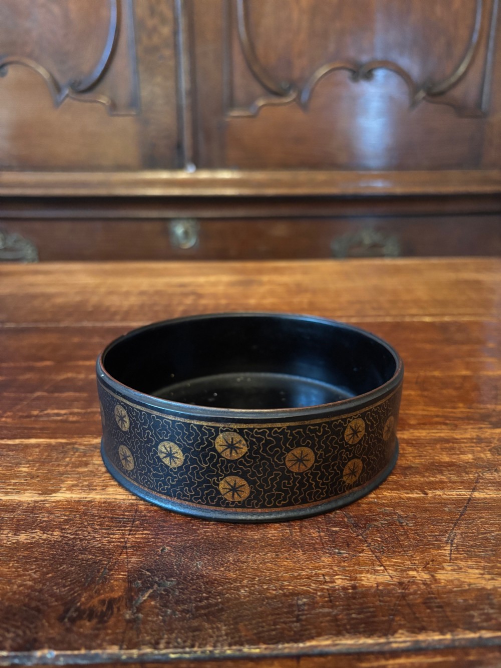 A circular black lacquered antique wine coaster decorated with gold star motifs and vermicelli patterns around the exterior side. View V