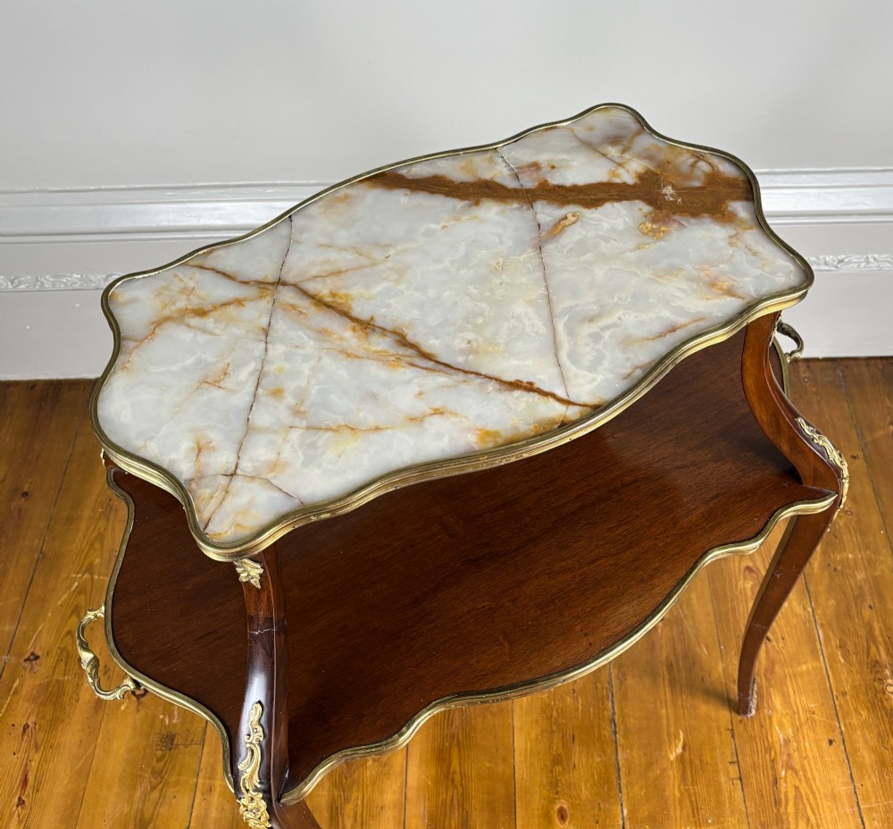 A French Napoleon III style two-tier tea table featuring an onyx inset top shelf, a mahogany lower shelf with side handles, cabriole legs, and gilded bronze mounts. View III