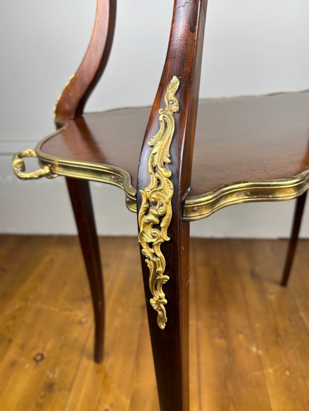 A French Napoleon III style two-tier tea table featuring an onyx inset top shelf, a mahogany lower shelf with side handles, cabriole legs, and gilded bronze mounts. View V