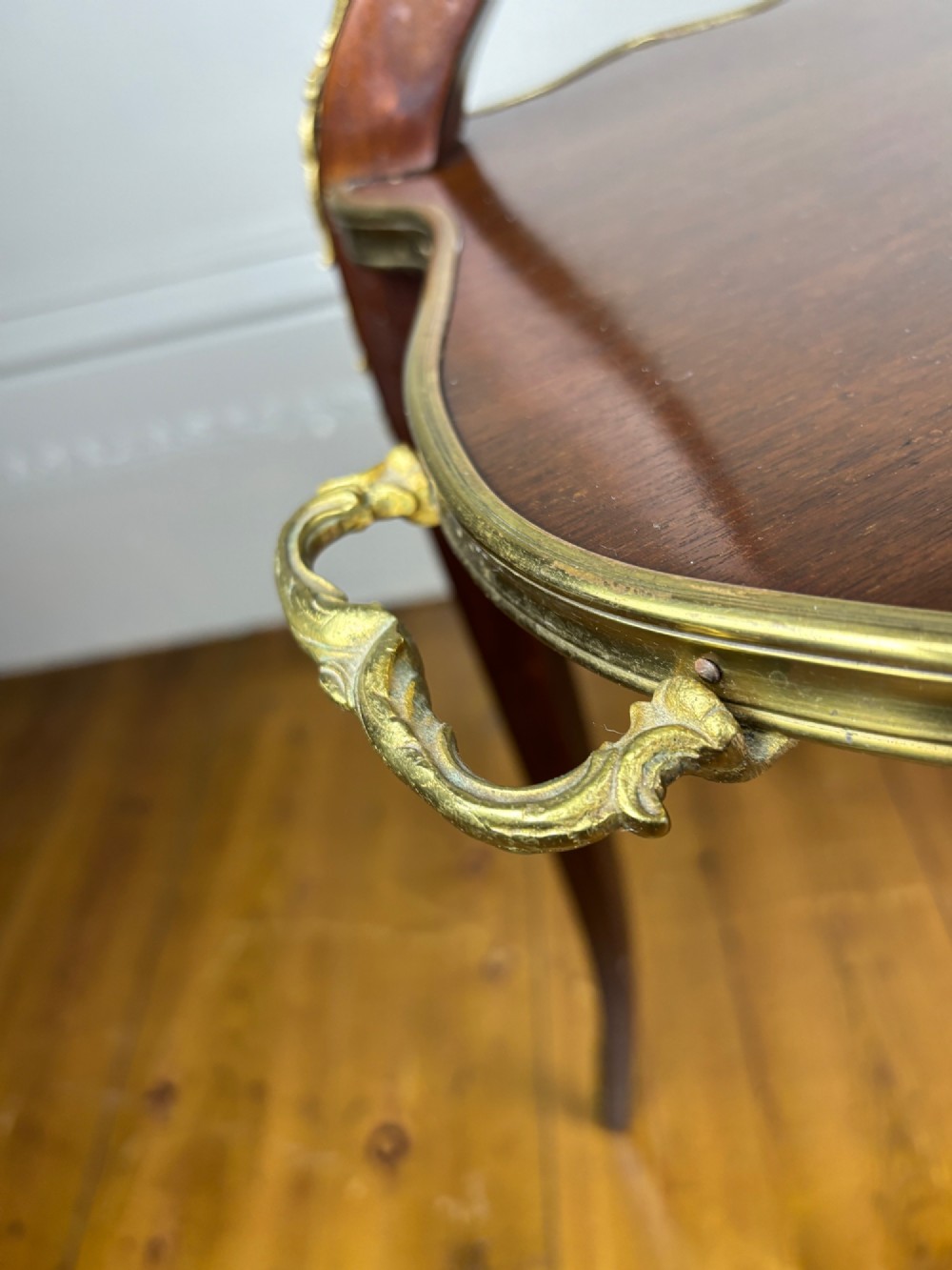 A French Napoleon III style two-tier tea table featuring an onyx inset top shelf, a mahogany lower shelf with side handles, cabriole legs, and gilded bronze mounts. View VI