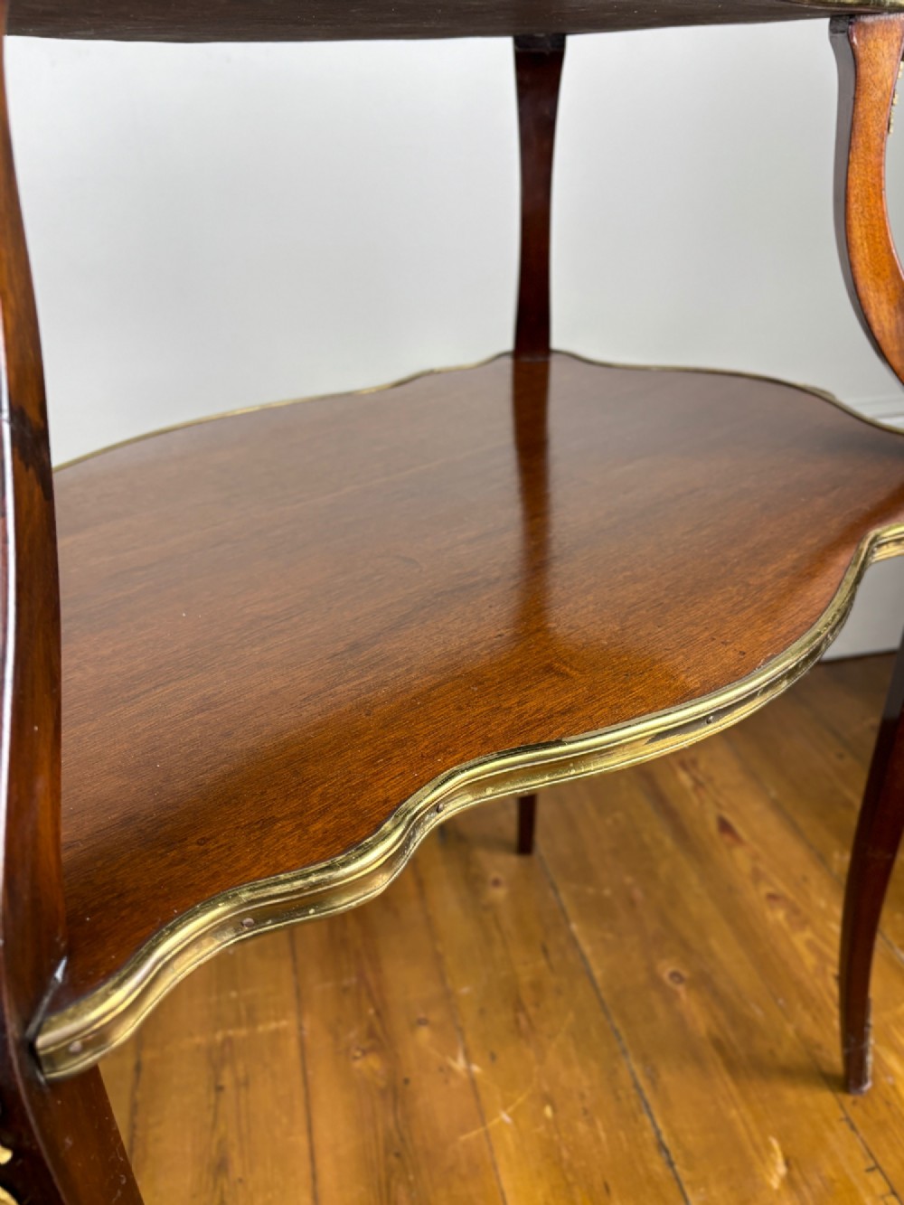 A French Napoleon III style two-tier tea table featuring an onyx inset top shelf, a mahogany lower shelf with side handles, cabriole legs, and gilded bronze mounts. View VII