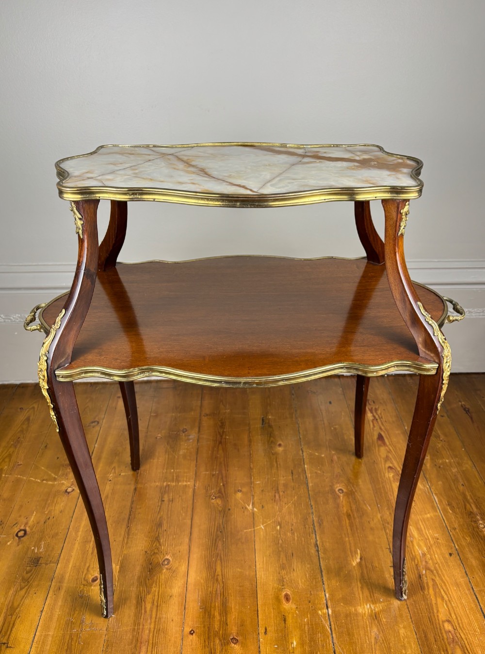 A French Napoleon III style two-tier tea table featuring an onyx inset top shelf, a mahogany lower shelf with side handles, cabriole legs, and gilded bronze mounts. View VIII