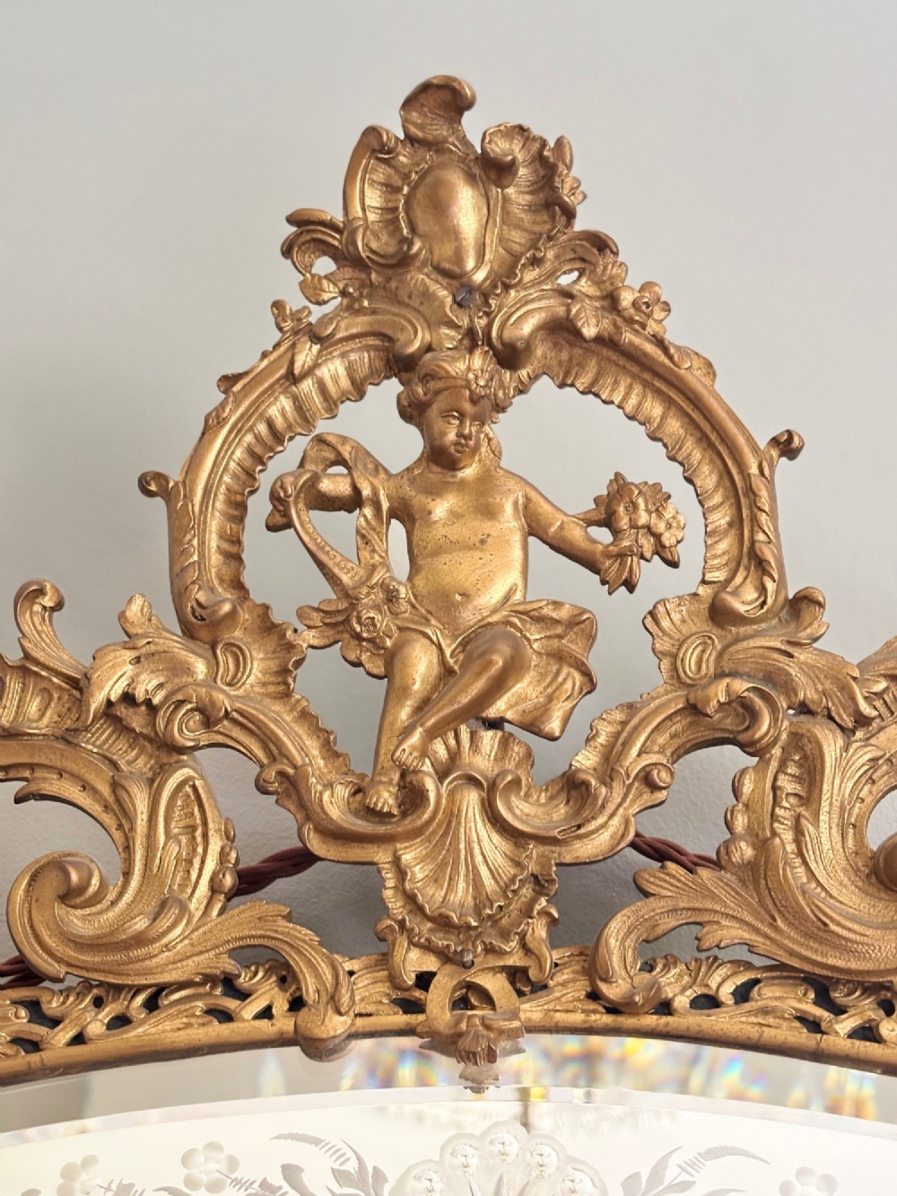 A French Louis XV style wall mirror featuring a gilt bronze frame with a cherub cresting and floral etched glass border plates. View II