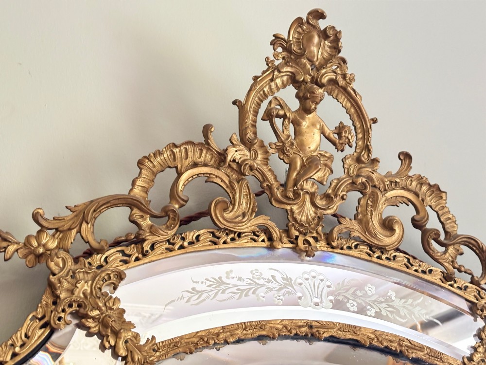 A French Louis XV style wall mirror featuring a gilt bronze frame with a cherub cresting and floral etched glass border plates. View VI