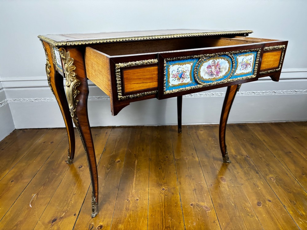 A Louis XV style rosewood writing table featuring cabriole legs, gilt bronze ormolu mounts, and turquoise porcelain plaques. View XV
