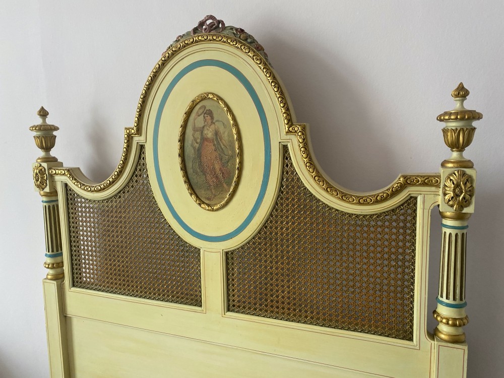 A pair of antique cream and gilt painted single beds featuring caned headboards with central painted portrait medallions and carved paw feet. View IV