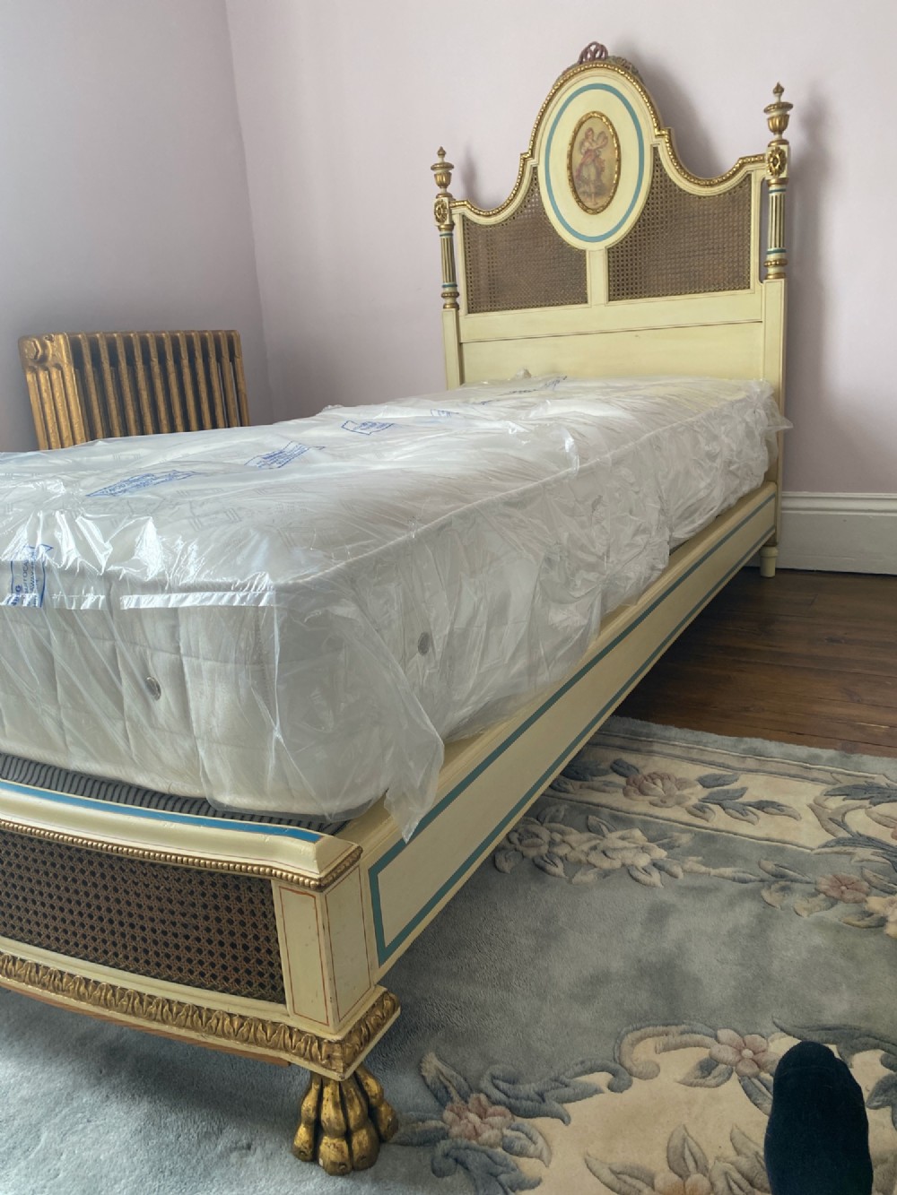 A pair of antique cream and gilt painted single beds featuring caned headboards with central painted portrait medallions and carved paw feet. View VI