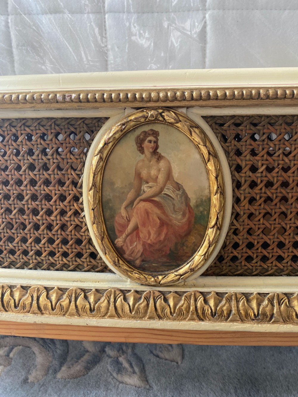 A pair of antique cream and gilt painted single beds featuring caned headboards with central painted portrait medallions and carved paw feet. View IX