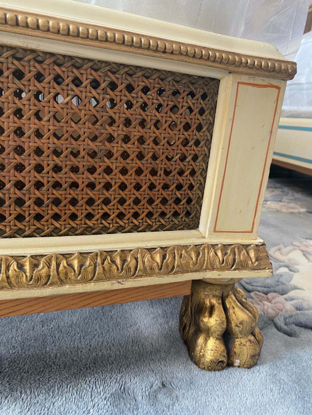 A pair of antique cream and gilt painted single beds featuring caned headboards with central painted portrait medallions and carved paw feet. View X