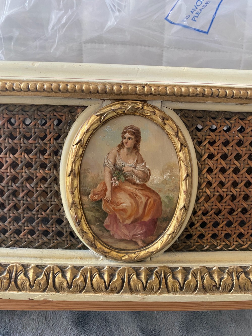A pair of antique cream and gilt painted single beds featuring caned headboards with central painted portrait medallions and carved paw feet. View XII