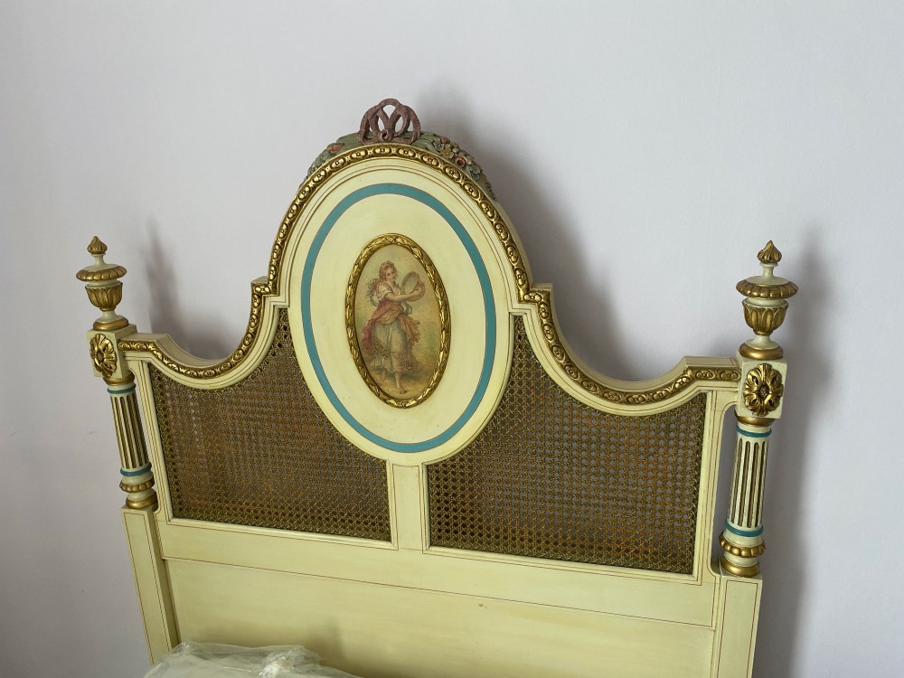 A pair of antique cream and gilt painted single beds featuring caned headboards with central painted portrait medallions and carved paw feet. View XIV