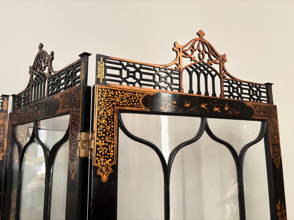 A four-fold black lacquered screen with Chinese Chippendale fretwork crestings, glazed upper panels, and incised gold chinoiserie landscape scenes. View II
