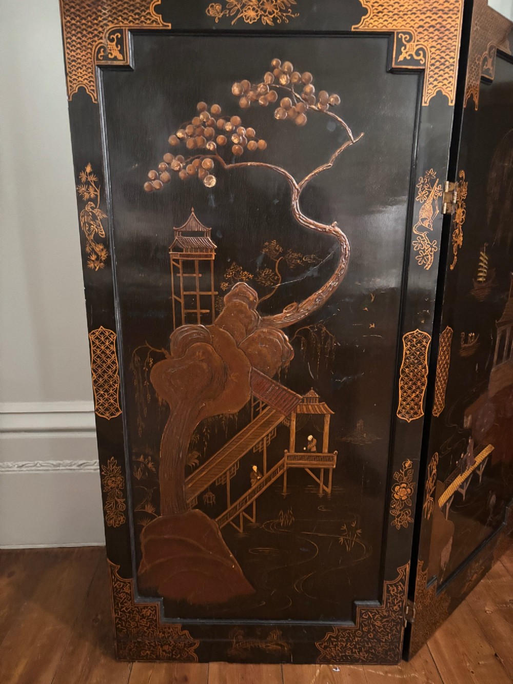 A four-fold black lacquered screen with Chinese Chippendale fretwork crestings, glazed upper panels, and incised gold chinoiserie landscape scenes. View V