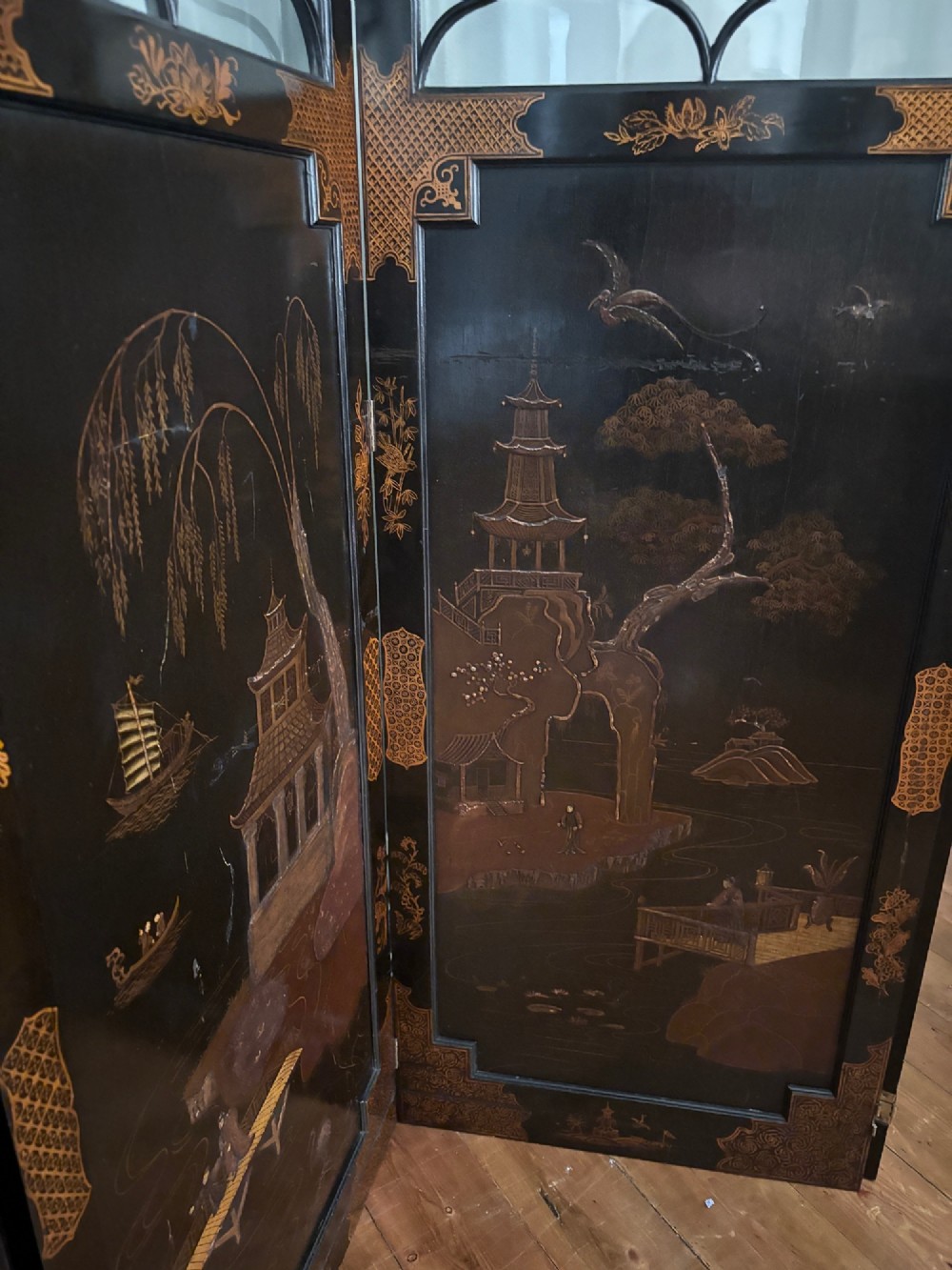 A four-fold black lacquered screen with Chinese Chippendale fretwork crestings, glazed upper panels, and incised gold chinoiserie landscape scenes. View VII