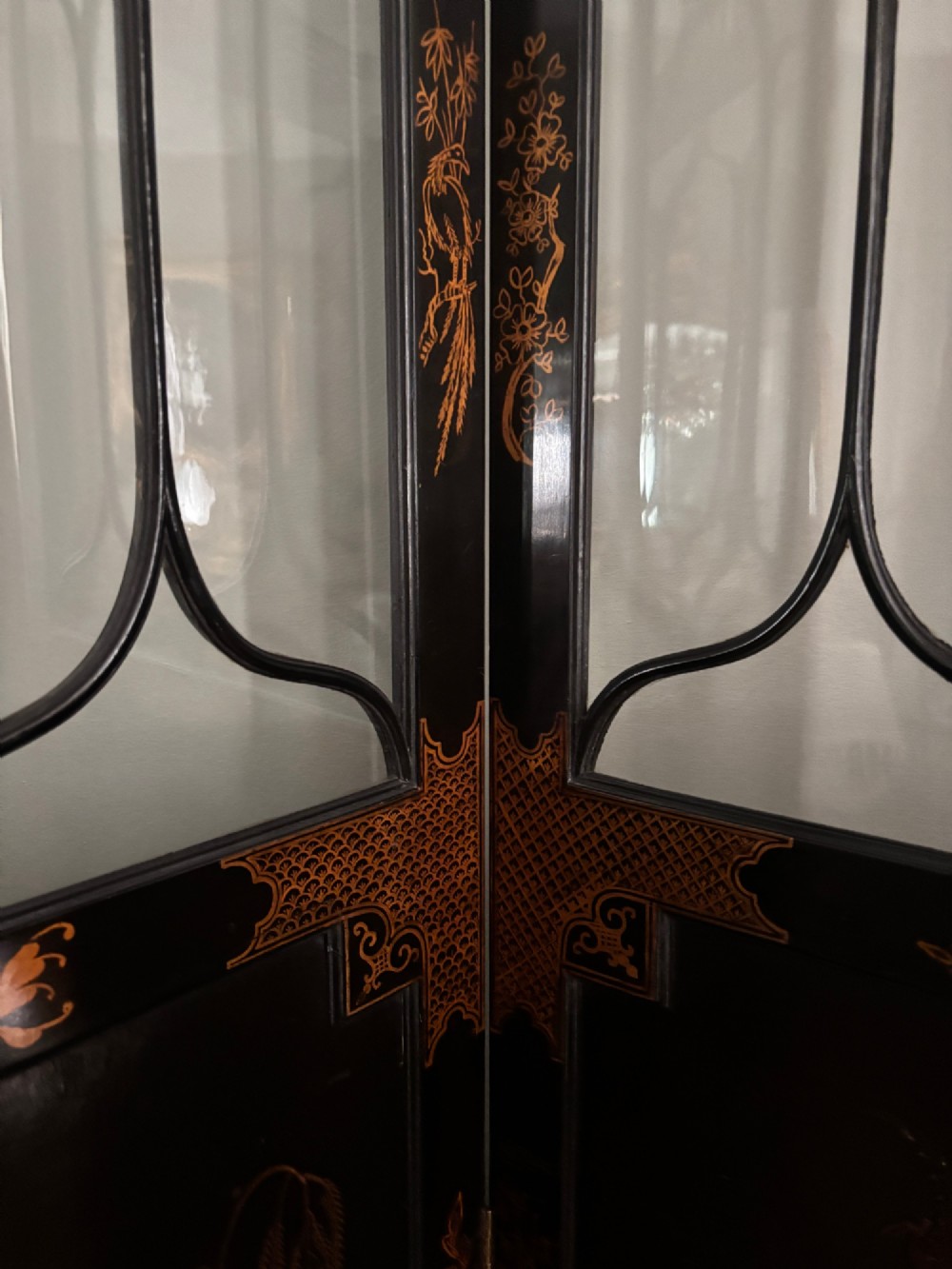 A four-fold black lacquered screen with Chinese Chippendale fretwork crestings, glazed upper panels, and incised gold chinoiserie landscape scenes. View X