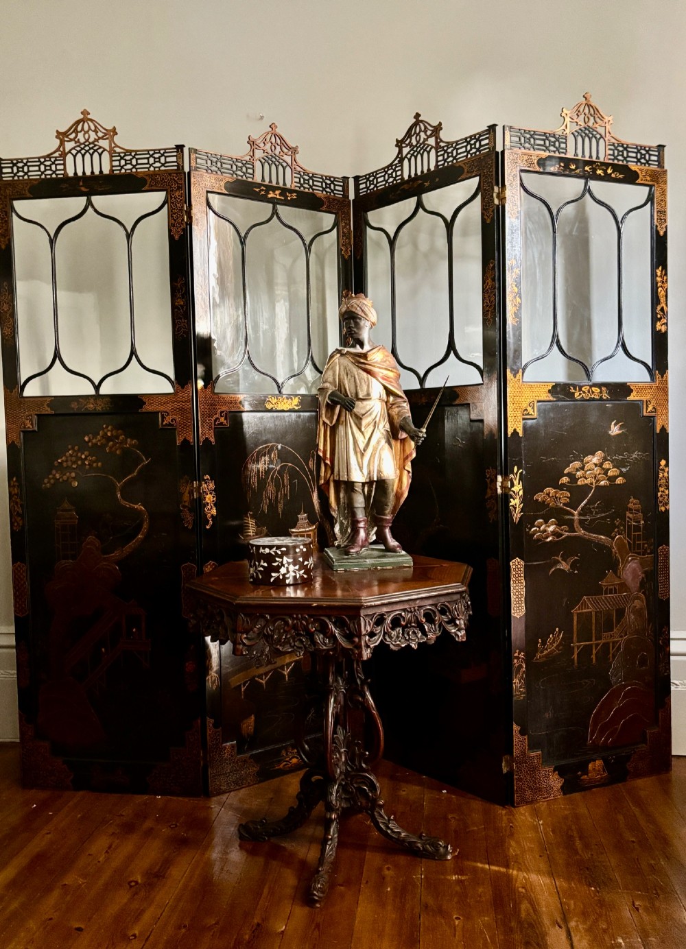 A four-fold black lacquered screen with Chinese Chippendale fretwork crestings, glazed upper panels, and incised gold chinoiserie landscape scenes. View XI