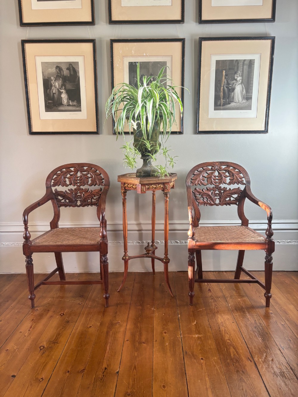 A pair of carved hardwood open armchairs featuring intricate openwork foliate backrests, swept arms, woven cane seats, and turned front legs. View VIII