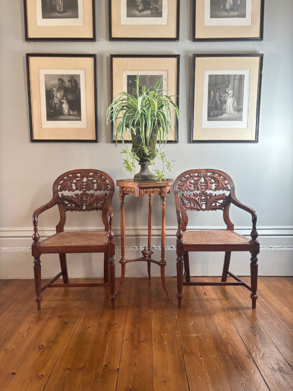 A pair of carved hardwood open armchairs featuring intricate openwork foliate backrests, swept arms, woven cane seats, and turned front legs. View IX