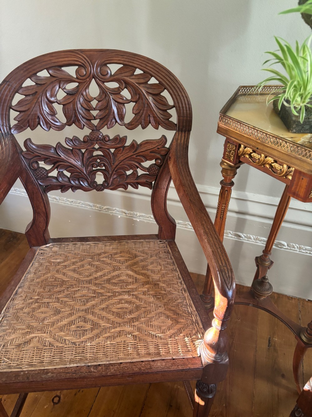 A pair of carved hardwood open armchairs featuring intricate openwork foliate backrests, swept arms, woven cane seats, and turned front legs. View XI
