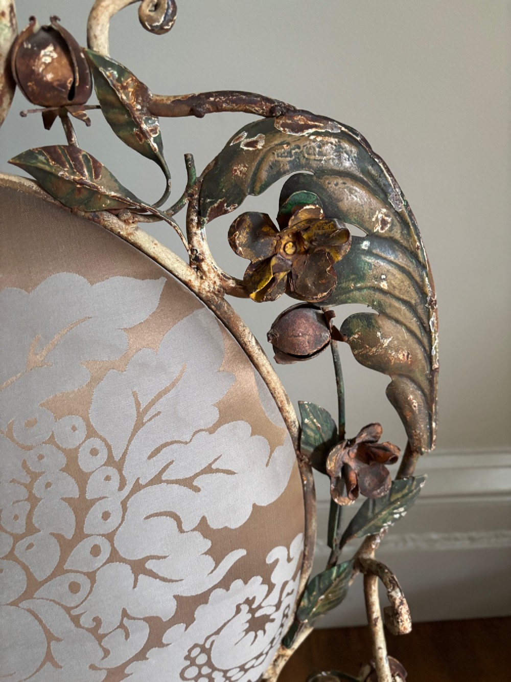 A pair of French wrought iron armchairs featuring cream painted scrolled frames, polychrome floral accents around oval backrests, and burgundy leather seats. View III