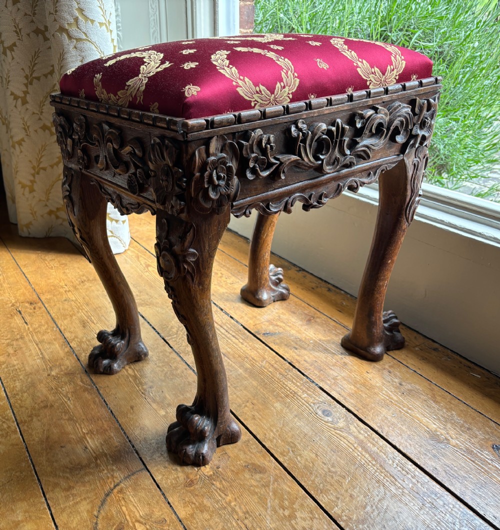 A Victorian Chippendale style carved wooden stool featuring cabriole legs with ball-and-claw feet and a rich burgundy upholstered seat patterned with gold wreaths. View III