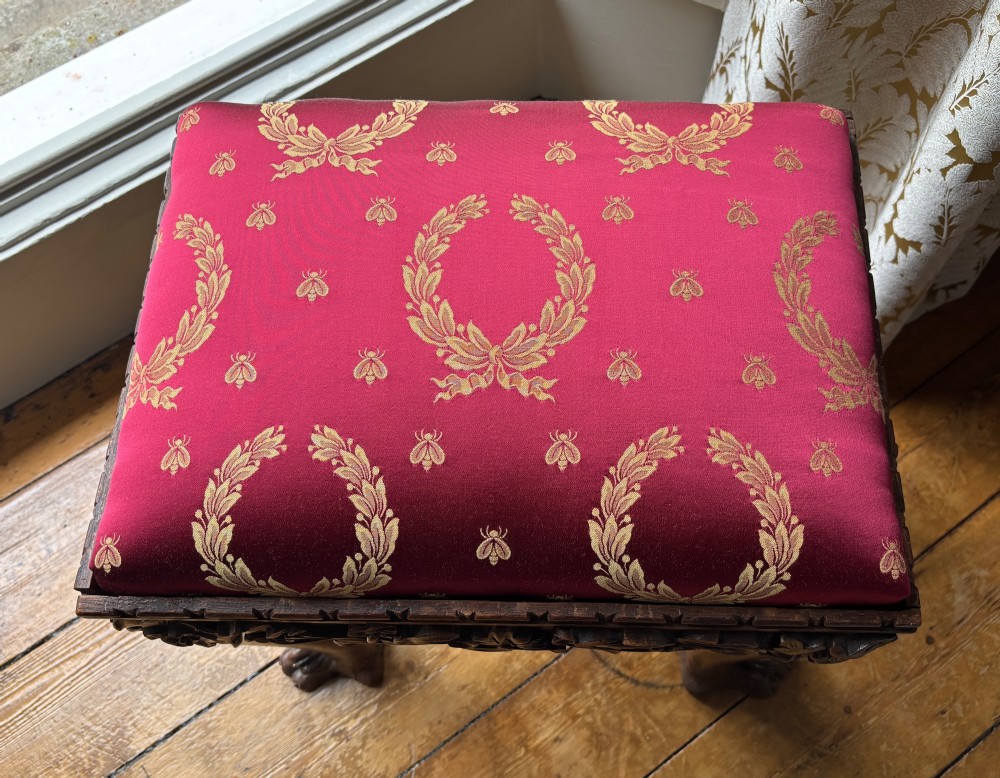 A Victorian Chippendale style carved wooden stool featuring cabriole legs with ball-and-claw feet and a rich burgundy upholstered seat patterned with gold wreaths. View V