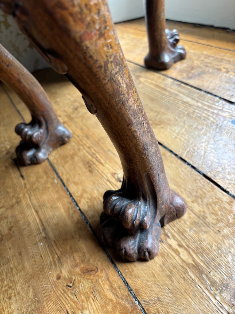 A Victorian Chippendale style carved wooden stool featuring cabriole legs with ball-and-claw feet and a rich burgundy upholstered seat patterned with gold wreaths. View VI