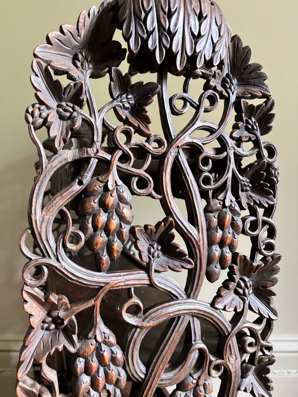 A tall mid-19th-century Anglo-Indian padauk wood shelving unit with three open tiers featuring deeply carved foliate aprons and intricate side supports. View XII